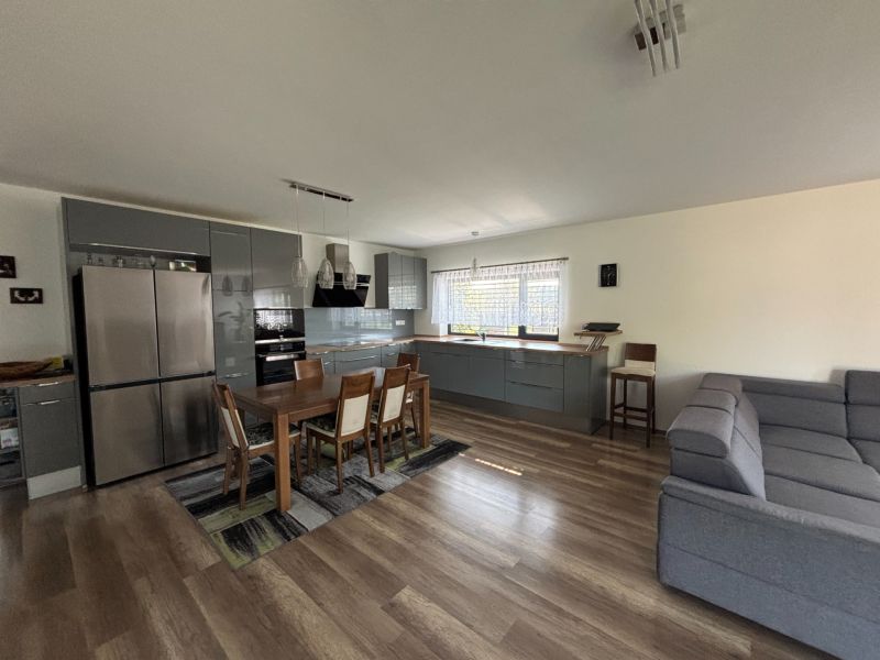 Open kitchen with a dining table and wood-patterned flooring in a family house.