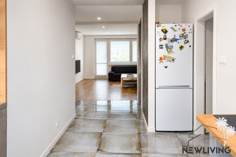 Interior of a 3-room apartment with a wooden decor floor and ceramics, living room in the background.