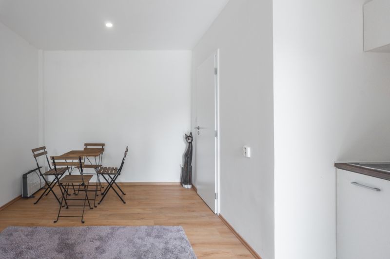 A simple interior with a wooden table and chairs on a floor with a wooden decor.