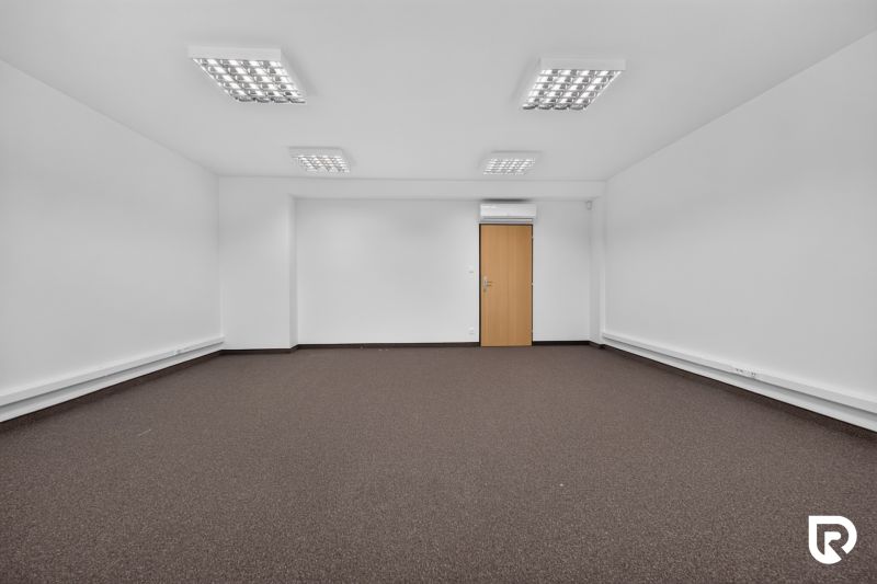 A spacious office with white walls and a brown carpet.