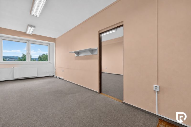 Offices with beige walls and a window with a view visible through it.