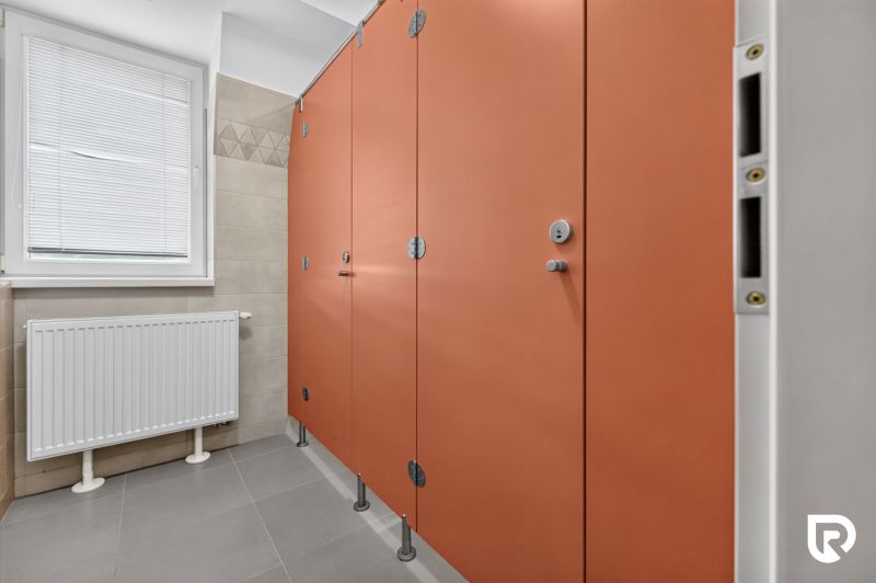 Orange stalls with doors in public restrooms in offices.