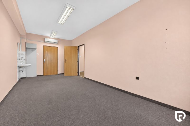 There is a sink, two doors, and light walls in the office.