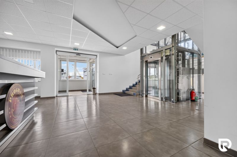 Office interiors with an elevator and entrance doors, floor with wood decor.