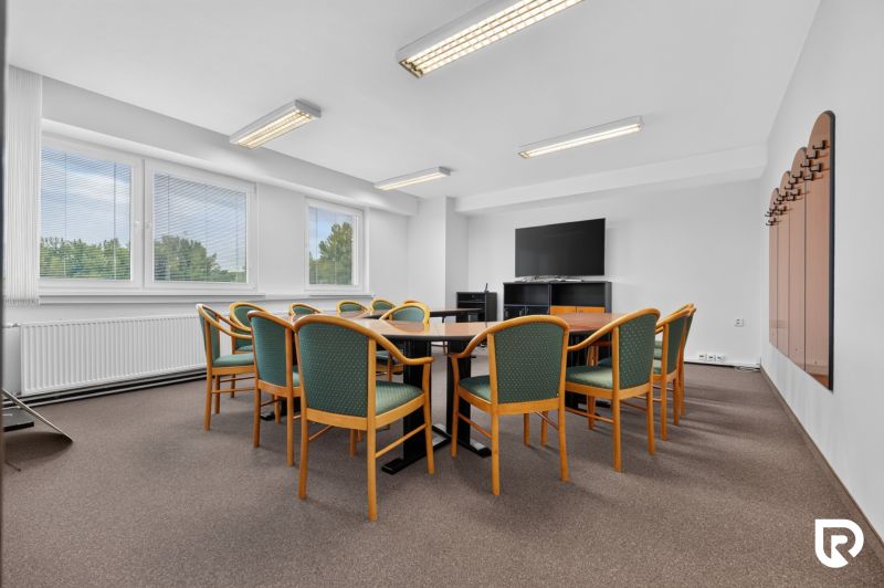 Conference room with windows, television, and a table with multiple chairs in an office.