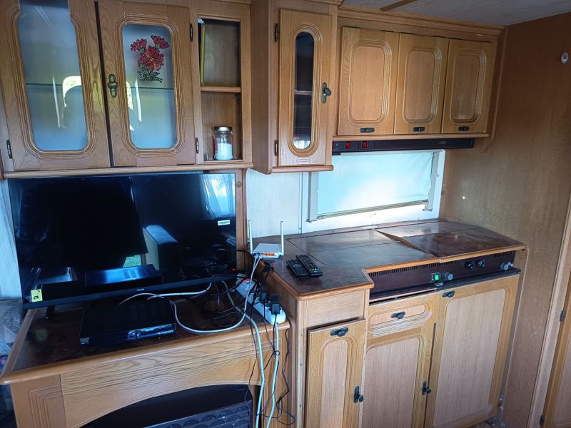 Interior of a caravan with wooden decor cabinets and electronics on the floor.