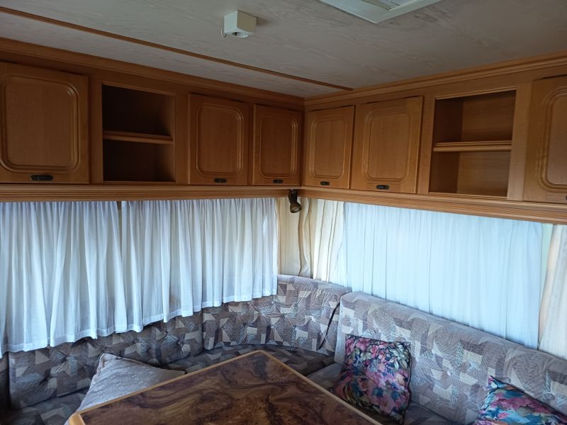 The interior of a caravan with a sofa, cabinets, and curtains, gardens, decorative table.
