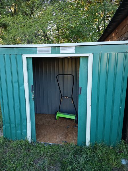 Gardens at Tatranská 201 in Zlaté Moravce with a metal shed and a lawnmower inside.