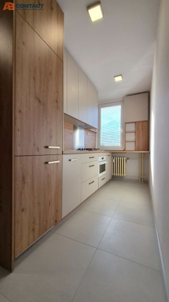 A kitchen in a studio apartment with a wood decor and built-in appliances.
