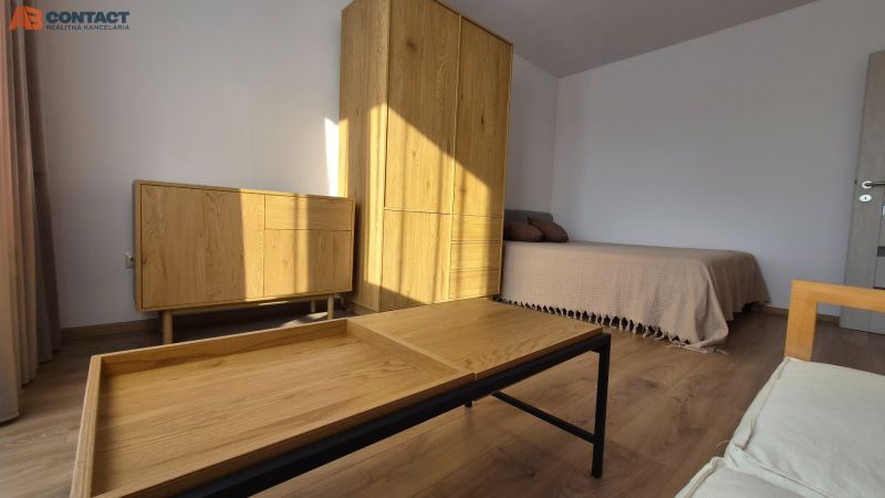Interior of a 1-room apartment with a bed, wooden furniture, and a floor with a wood decor.