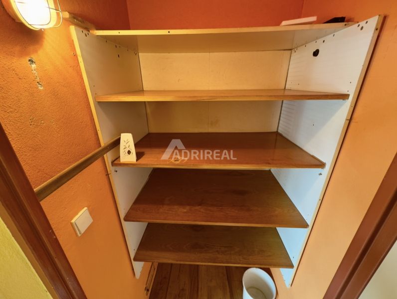 A shelf with four wooden shelves in a studio apartment, floor with wooden decor.