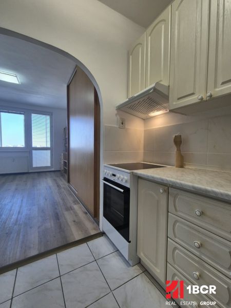 Kitchen corner in a studio apartment with a wooden decor floor and tiles.