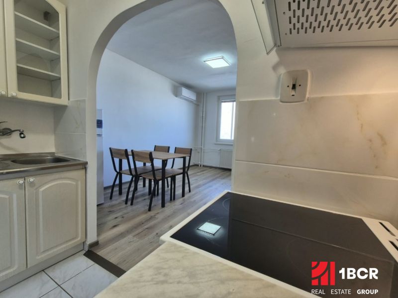 A kitchen with an open passage to the dining table, flooring with a wooden decor.
