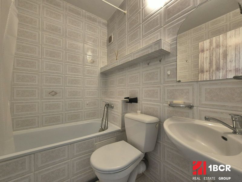 A bathroom in a studio apartment with a bathtub, sink, and toilet in muted colors.