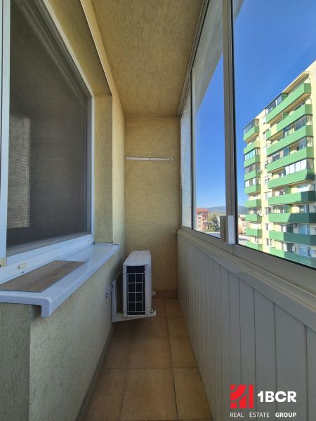 Enclosed balcony in a studio apartment with air conditioning and a view of the apartment buildings.