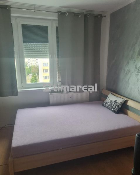 Bedroom in a 3-room apartment with a bed and a gray decorative pillow.