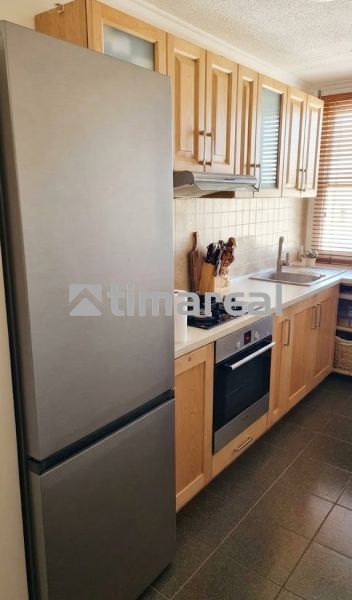 A kitchen unit in a 3-room apartment with wooden cabinets and appliances.