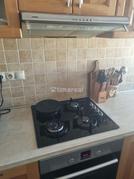 A kitchen unit with a hob and extractor in a 3-room apartment, tiled with tiles.