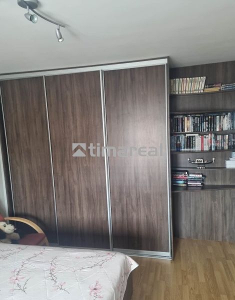 A wardrobe and a bookcase in a 3-room apartment, with a floor featuring a wooden decor.