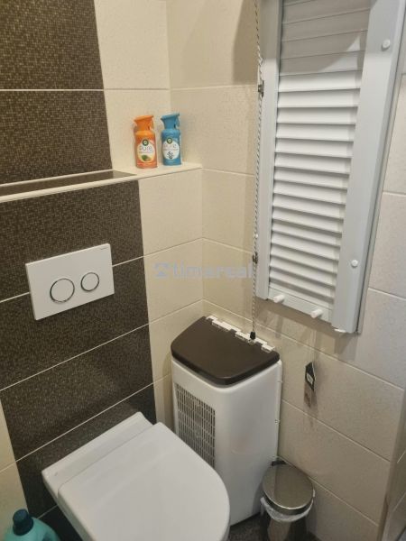 Bathroom with toilet in a 3-room apartment, cream-brown tiles and storage space.
