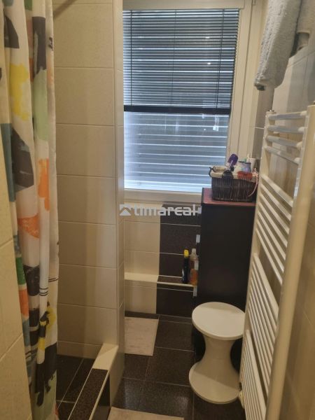 A bathroom with a tiled shower, curtain, and window in a 3-room apartment.