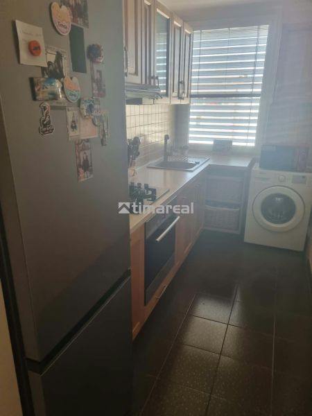 A kitchen in a 3-room apartment with a refrigerator, stove, and washing machine.
