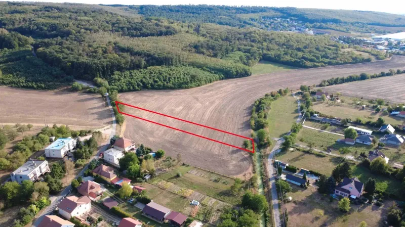 A view of agricultural and forest land in Podhájska, surrounded by houses and roads.