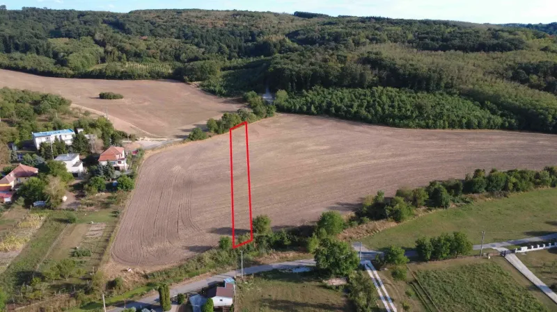 A rural view of agricultural and forest lands in Podhájska surrounding a settlement with family houses.