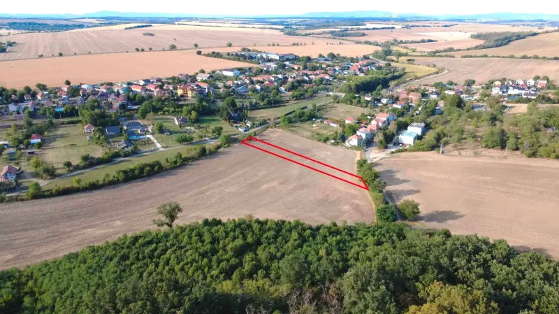 Aerial view of agricultural and forest lands in Podhájska, with the village in the background.