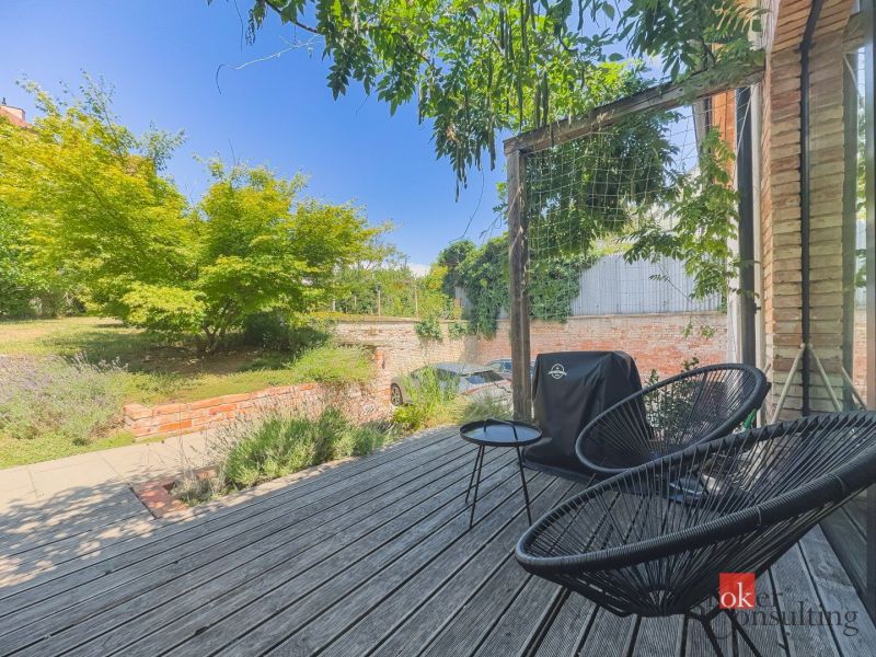A terrace in a 3-room apartment with wooden decor, a garden, and outdoor seating.