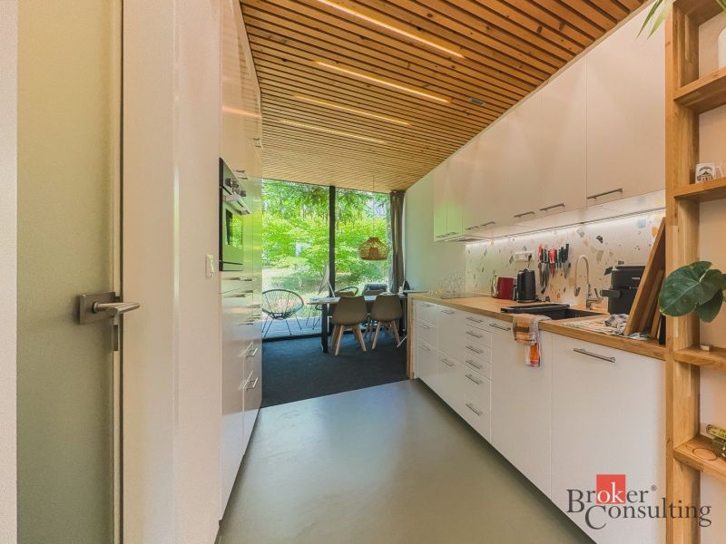 A kitchen in a 3-room apartment with a wooden ceiling and large glass windows.