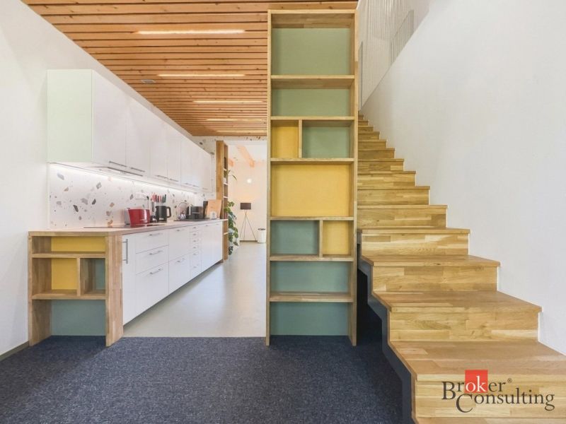 A kitchen with white cabinets and a wooden decor floor in a 3-room apartment.