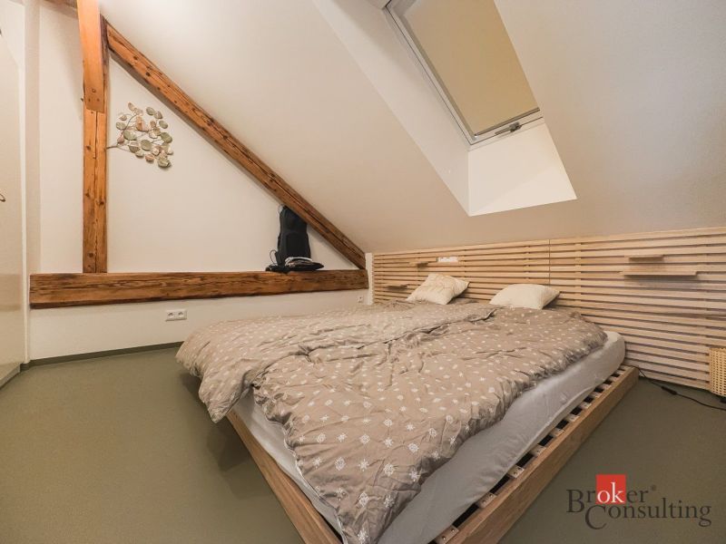 An attic bedroom with wooden elements and a double bed in a three-room apartment.