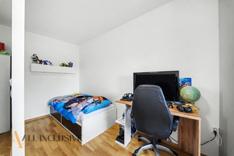 A children's room in a family house with a bed, a table, and a wooden decor floor.