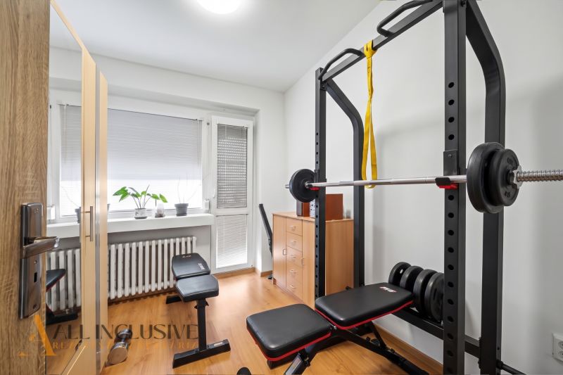 Home gym with a bench, dumbbells, and a wooden decor floor.