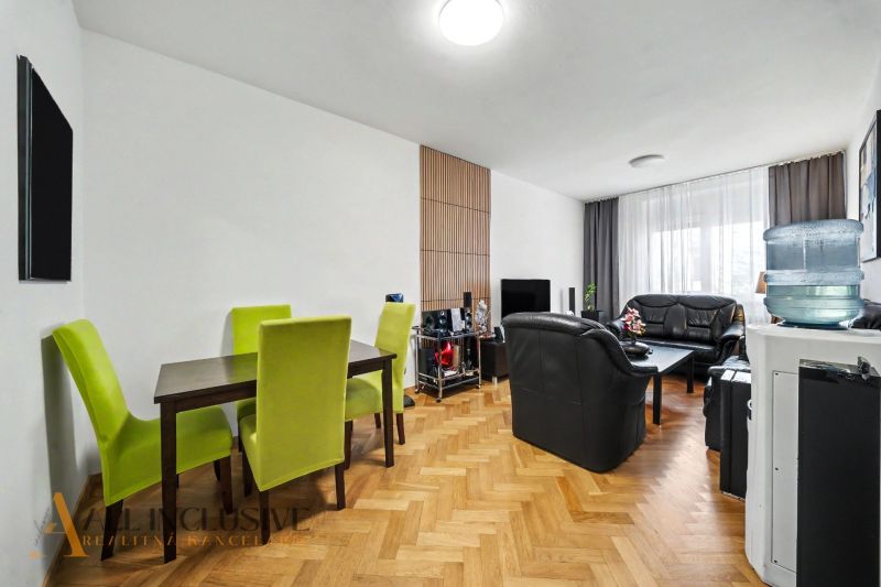 Living room with black sofas, dining table, and floor with wood decor.