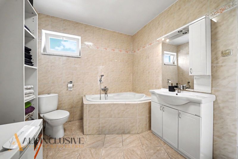 Bathroom with a corner bathtub, sink, and toilet in a family house.