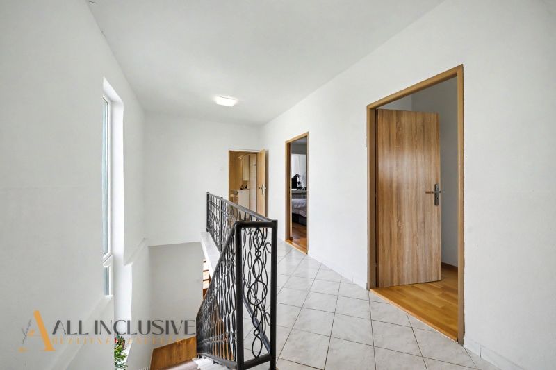 Hallway in a family house with a tiled floor and a staircase.