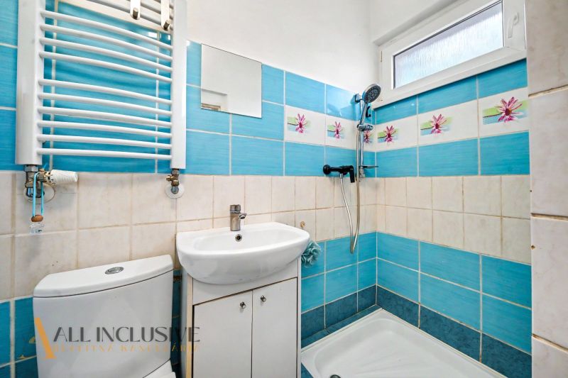 A bathroom in a family house with blue tiles and white fixtures.