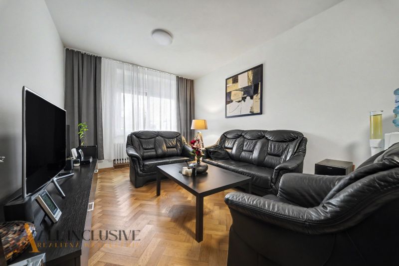 Living room in a family house with black leather furniture and a television.