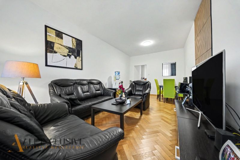 Living room in a family house with black leather furniture and a wooden decor floor.