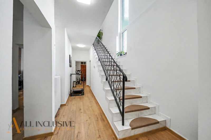 A staircase with white walls and a wood-patterned floor in a family house.