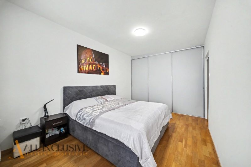 Bedroom with a large bed, a nightstand, and a wooden decor floor in a family house.