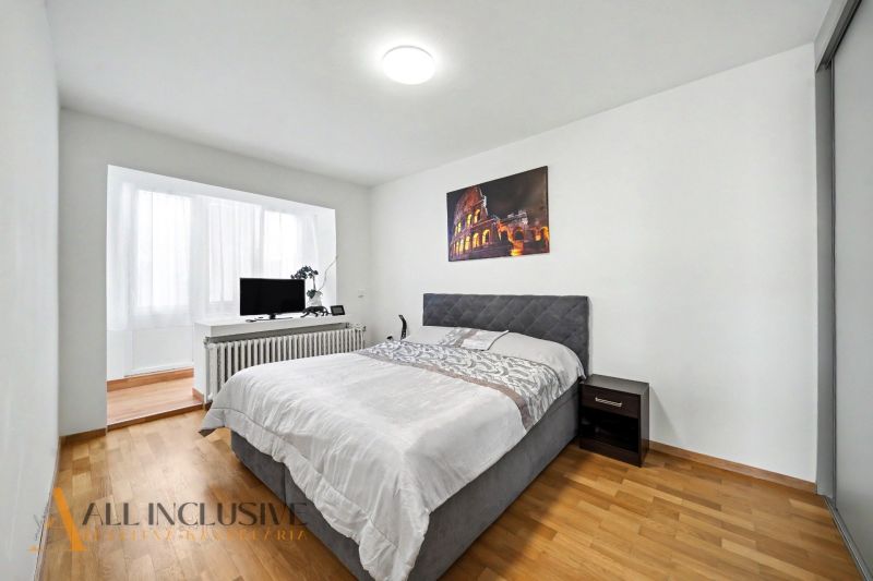 A bedroom with a wood-patterned floor and a painting in a family house.