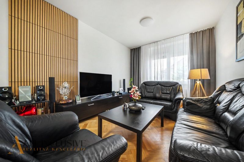 Living room of a family house with leather sofas and a wooden-patterned floor.