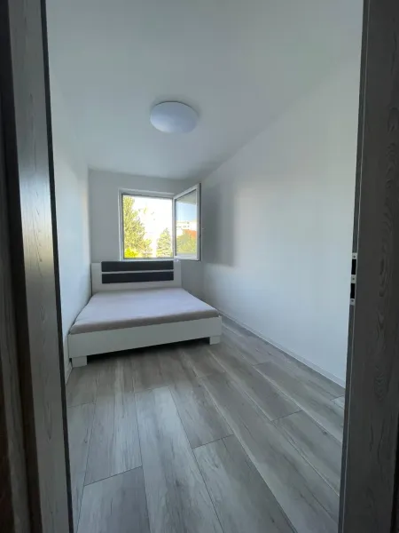 A bedroom with a bed and a wooden decor floor in a two-room apartment.