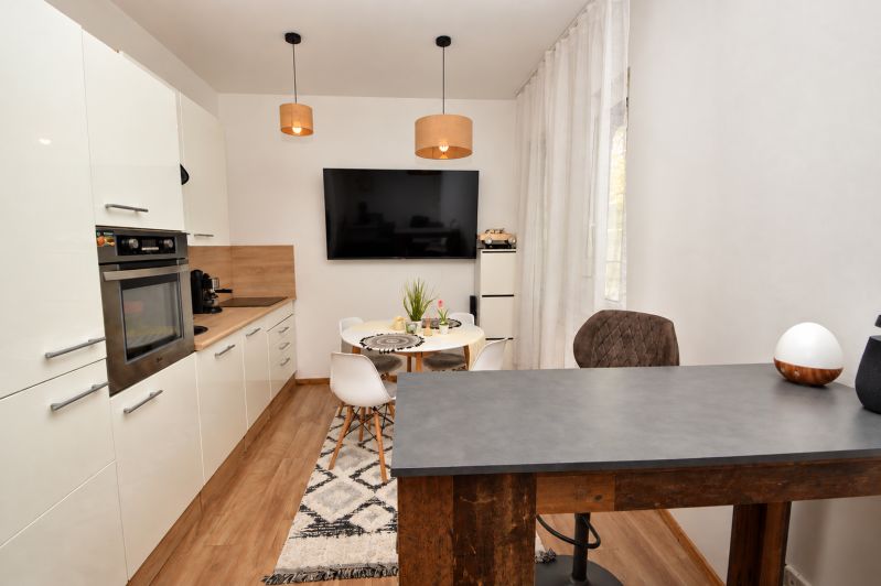 A kitchen in a studio apartment with a wood-patterned floor and a dining table.