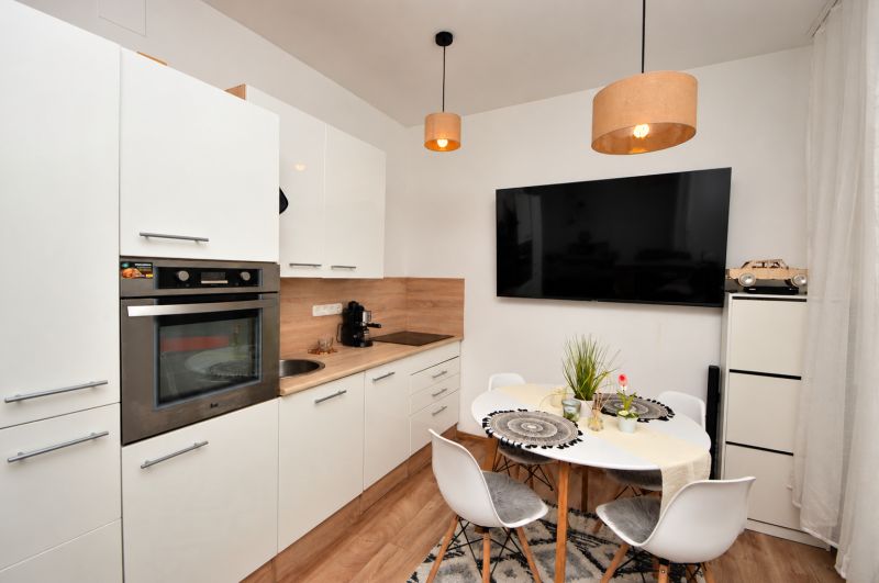 Compact kitchen in a studio apartment with wood-patterned flooring and a dining area.