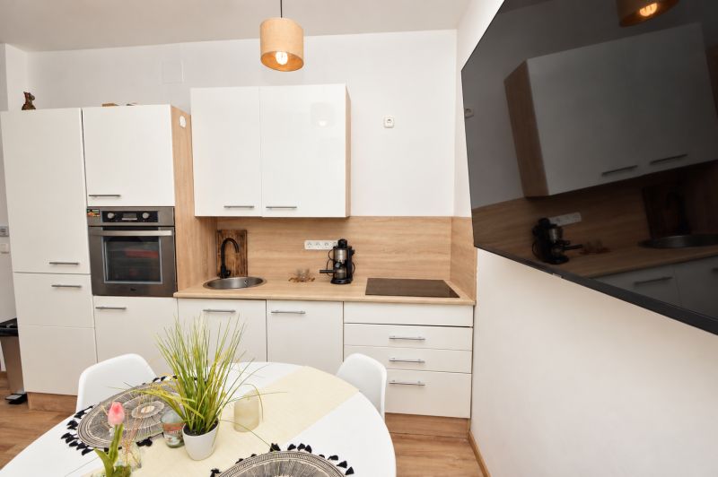 A kitchen unit in a studio apartment with white cabinets and a wood-patterned floor.
