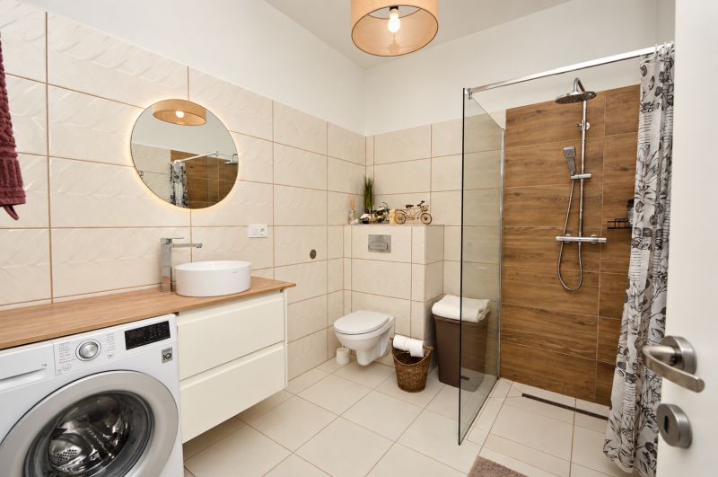 Bathroom with a washing machine, shower cabin, and wooden decor flooring in a studio apartment.